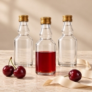 Butelka Elixir 50 ml – kilka małych przezroczystych butelek ze złotymi zakrętkami na blacie
